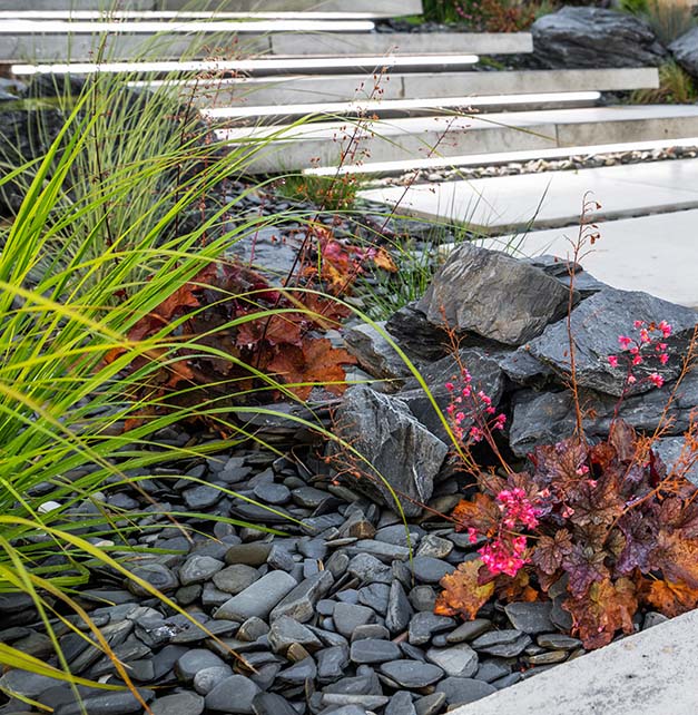 A charming garden scene with decorative rocks, diverse plants, and bright flowers